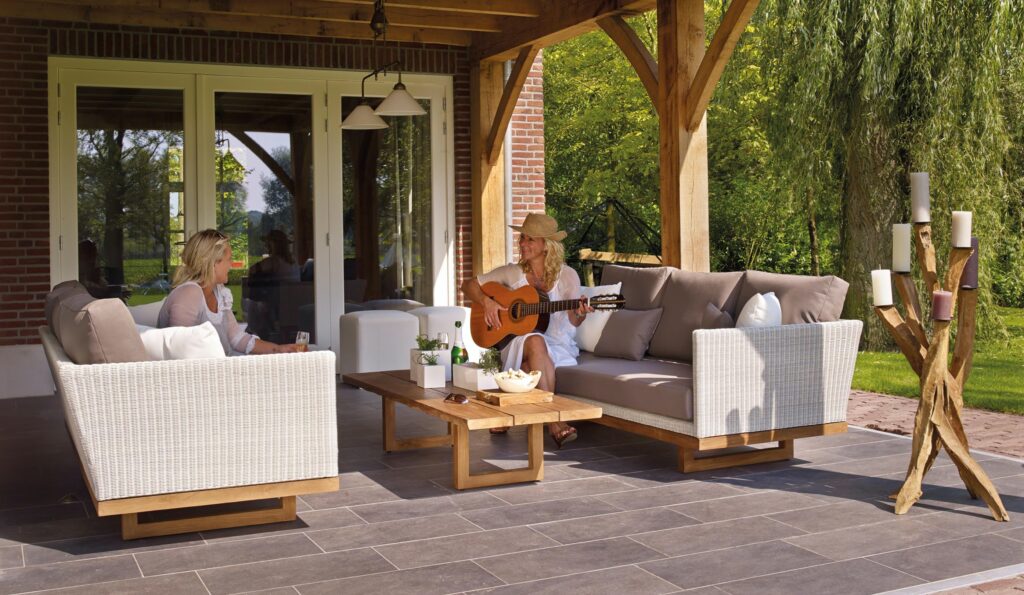 Woman playing guitar on an outdoor patio entertaining another woman
